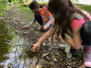 Two Girls explore rocks in a creek